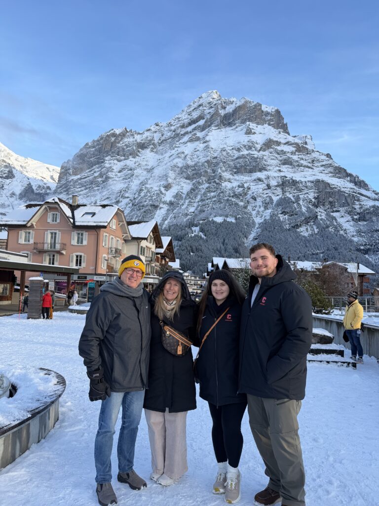 Rachel standing with her family above the village of Grindelwald, surrounded by Swiss Alps mountains, capturing a multigenerational family travel moment.