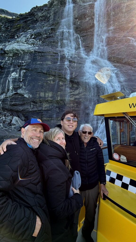 Rachel Friem with her father and two brothers beside a waterfall during their 2025 Greenland family trip.