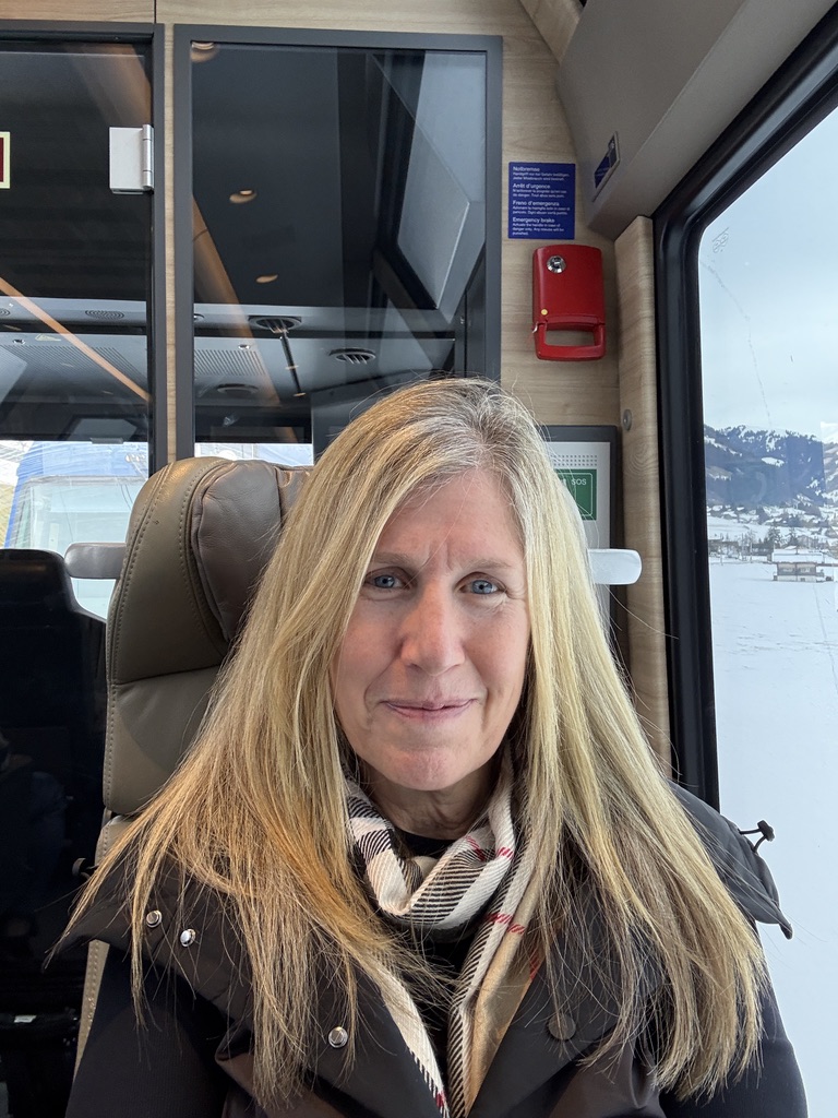 Rachel Friem, creator of Gen X Travel Mom, sitting on a train while traveling in Europe.